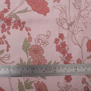 Pode incluir: Tecido rosa com um padr&atilde;o floral com flores vermelhas e verdes. Uma r&eacute;gua &eacute; colocada sobre o tecido para mostrar a escala.