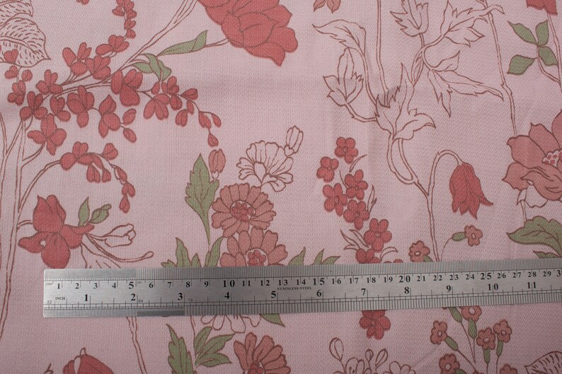 Pode incluir: Tecido rosa com um padr&atilde;o floral com flores vermelhas e verdes. Uma r&eacute;gua &eacute; colocada sobre o tecido para mostrar a escala.