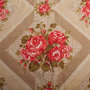 Könnte beinhalten: Ein Blumenmuster mit roten Rosen und grünen Blättern auf beigem Hintergrund. Das Design ist in einem sich wiederholenden Rautenmuster mit einem gesprenkelten Effekt angeordnet. Die Rosen sind in voller Blüte.