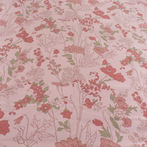 Pode incluir: Tecido rosa com um padr&atilde;o floral com flores vermelhas e folhas verdes.