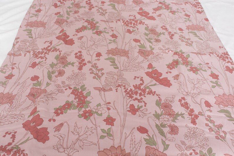 Pode incluir: Tecido rosa com um padr&atilde;o floral com flores vermelhas e folhas verdes.