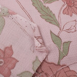 Pode incluir: Close-up de um tecido rosa com um padr&atilde;o floral. O tecido tem uma textura sutil e apresenta flores rosa e verdes.