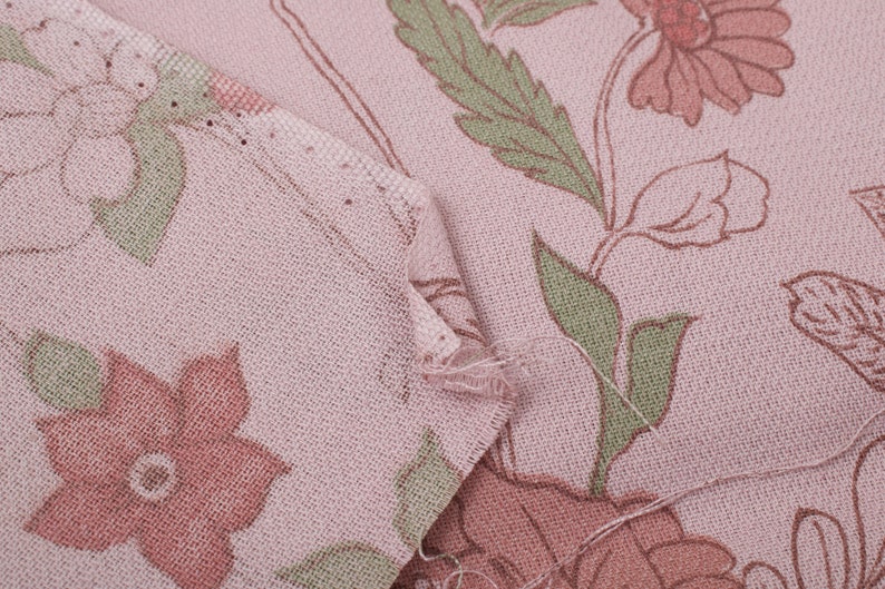 Pode incluir: Close-up de um tecido rosa com um padr&atilde;o floral. O tecido tem uma textura sutil e apresenta flores rosa e verdes.