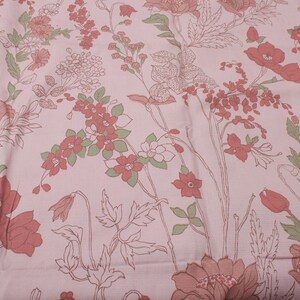 Pode incluir: Tecido rosa com um padr&atilde;o floral com flores vermelhas e verdes. As flores s&atilde;o contornadas em branco e t&ecirc;m um estilo vintage.