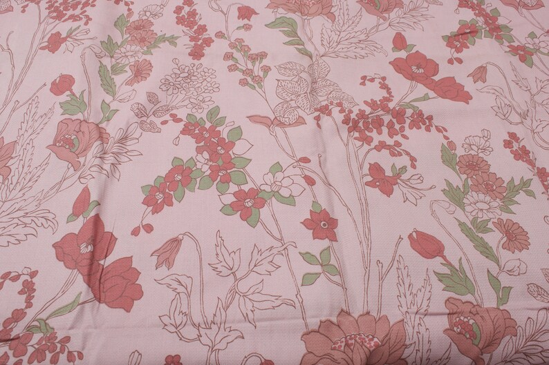 Pode incluir: Tecido rosa com um padr&atilde;o floral com flores vermelhas e verdes. As flores s&atilde;o contornadas em branco e t&ecirc;m um estilo vintage.