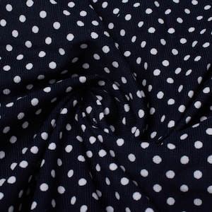 Puede incluir: Tela azul marino con estampado de lunares blancos. La tela es texturizada y tiene un ligero brillo.