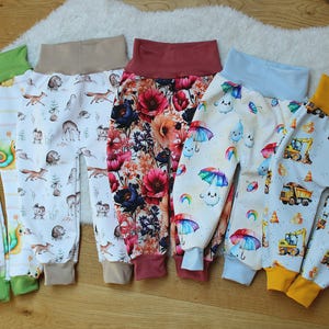 Könnte beinhalten: Fünf Paar bunte Leggings mit verschiedenen Mustern. Die Leggings sind aus weichem, dehnbarem Stoff und perfekt für den Alltag. Die Muster umfassen Schnecken, Tiere, Blumen, Regenschirme und Baufahrzeuge.