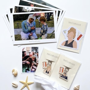 May include: A collection of printed photographs featuring scenes with a person in a rabbit costume and a group of people, alongside two clear plastic pouches containing acrylic keychains and a sticker, all labeled with the text That's delicate.