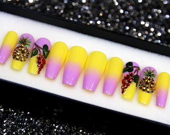 May include: Set of ten long, coffin-shaped false nails with a gradient design. The nails are painted a light pink at the base and fade to a bright yellow at the tip. Each nail is decorated with a 3D pineapple and red berry design with rhinestones.