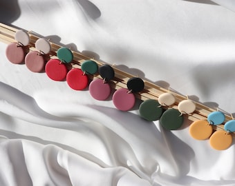 May include: A set of 10 pairs of handmade polymer clay earrings. Each pair features two round discs in different colors, including beige, pink, red, green, blue, and black.