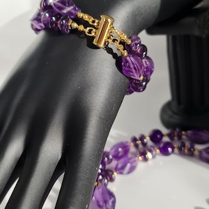 May include: A double-strand amethyst necklace and bracelet set with gold accents. The necklace and bracelet are made of faceted amethyst beads.