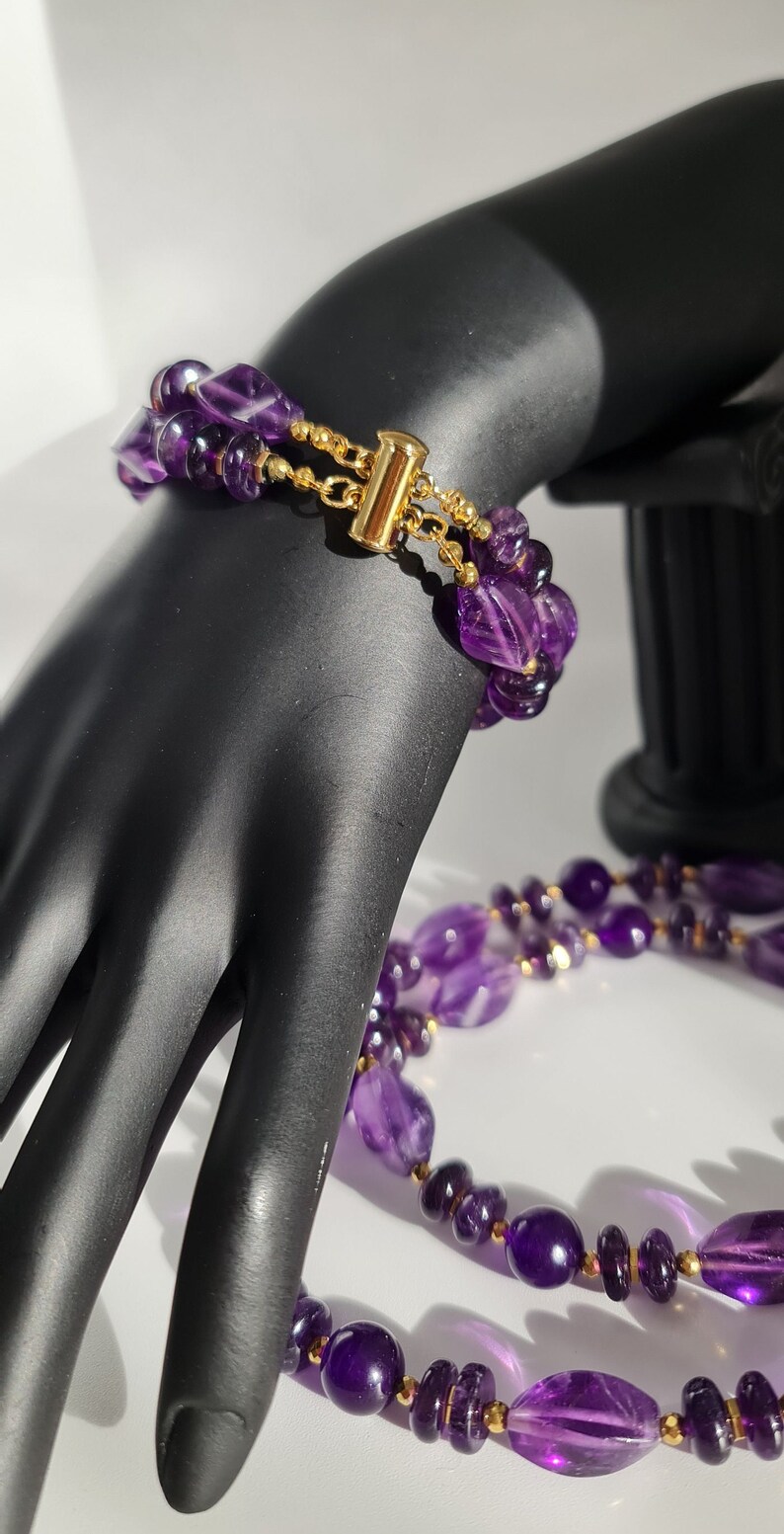 May include: A double-strand amethyst necklace and bracelet set with gold accents. The necklace and bracelet are made of faceted amethyst beads.