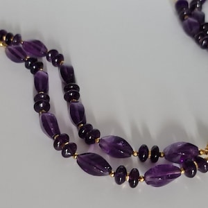 May include: A double-strand amethyst bracelet with gold accents. The bracelet is made of oval-shaped amethyst beads and gold spacers.