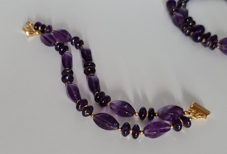 May include: A double-strand amethyst bracelet with gold accents. The bracelet is made of oval-shaped amethyst beads and gold spacers.