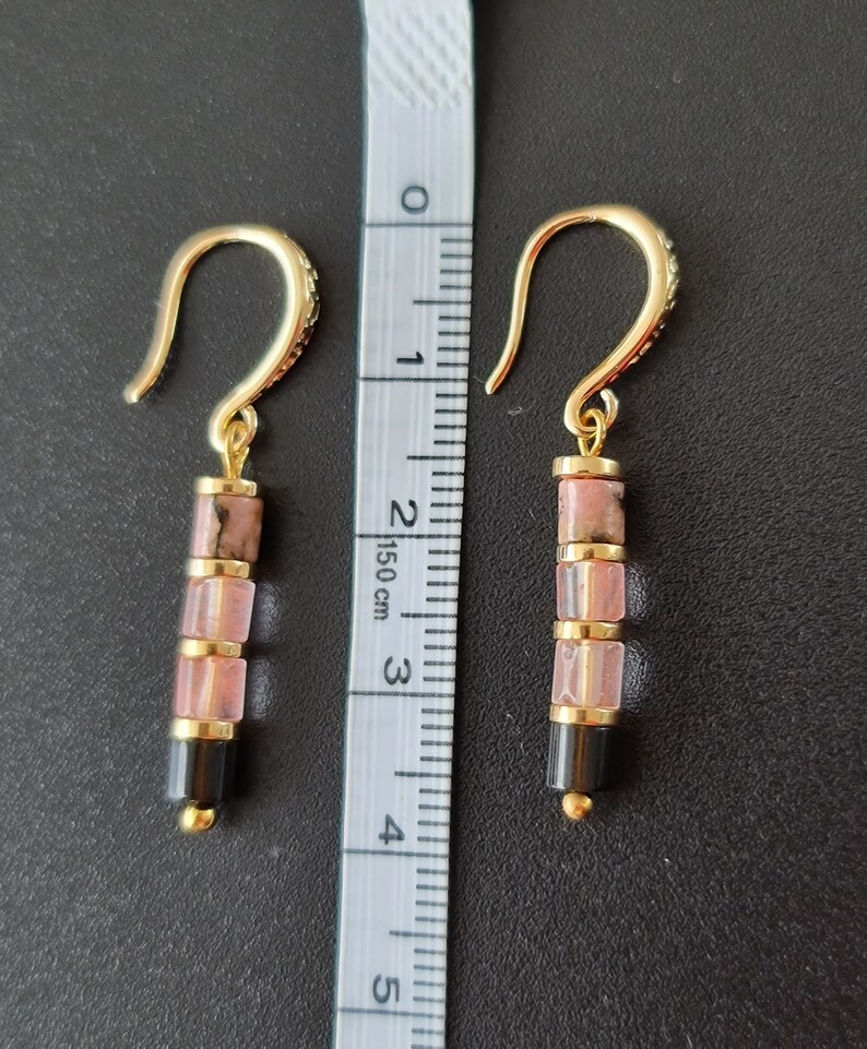 May include: Gold earrings with pink and black gemstone beads. The earrings are approximately 3 cm long.