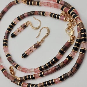 May include: A pink and black beaded necklace and matching earrings. The necklace is made of pink and black beads, and the earrings are made of pink beads with gold hooks.