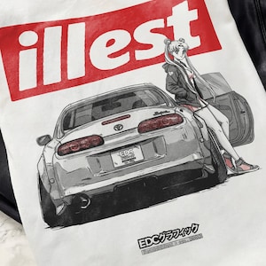 Könnte beinhalten: Weißes T-Shirt mit einer Grafik eines silbernen Sportwagens und einer Cartoonfigur. Das Wort "illest" befindet sich in einem roten Rechteck. Der Text "EDC グラフィック" steht unten.