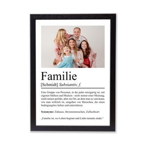 Könnte beinhalten: Ein gerahmter Druck mit einem Familienporträt über dem deutschen Wort "Familie". Der schwarze Rahmen umgibt ein Foto einer lächelnden Familie. Unter dem Foto befindet sich eine Definition von Familie auf Deutsch.
