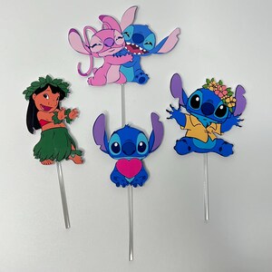 Puede incluir: Conjunto de cinco adornos para tartas de Stitch y Angel. Los adornos representan a Stitch y Angel en varias poses, incluyendo a Stitch sosteniendo un coraz&oacute;n, Stitch con un collar de flores y Stitch y Angel abraz&aacute;ndose. Los adornos est&aacute;n hechos de cart&oacute;n y est&aacute;n unidos a palos de pl&aacute;stico transparente.