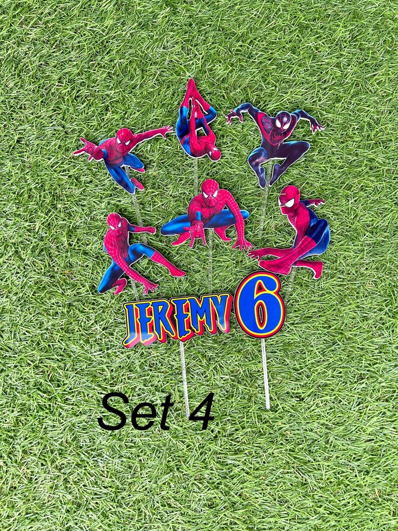 May include: Set of 7 red and blue Spiderman cake toppers with the name Jeremy and the number 6. The toppers are on sticks and are ready to be placed on a cake. Set 4 is written below the toppers.