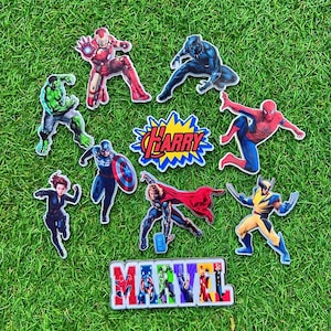 Puede incluir: Una colecci&oacute;n de pegatinas de personajes de superh&eacute;roes Marvel de colores sobre un fondo de hierba verde. Las pegatinas incluyen a Iron Man, Black Panther, Hulk, Capit&aacute;n Am&eacute;rica, Thor, Spider-Man, Wolverine y Black Widow. Tambi&eacute;n se muestra la palabra "Marvel".