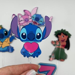 Puede incluir: Un conjunto de cinco adornos para tartas de personajes de dibujos animados azules y rosas con Stitch, Angel y Lilo de la pel&iacute;cula de Disney Lilo & Stitch. Los adornos est&aacute;n en palos de pl&aacute;stico transparentes.