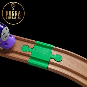 Puede incluir: Una pieza de vía de plástico verde para un tren de juguete de madera. La pieza de vía está diseñada para conectar dos piezas de vía rectas para crear una vía curva.
