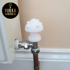 May include: A white mushroom-shaped radiator bleed valve key. The key is made of a smooth, solid material and is designed to fit on a radiator valve. The key is a decorative and functional item.