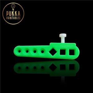 Puede incluir: Un objeto verde brillante impreso en 3D con una serie de agujeros, un rombo y dos cuadrados. Un tornillo blanco está insertado en el objeto. El logotipo de Pukka Printables está en la esquina superior izquierda.