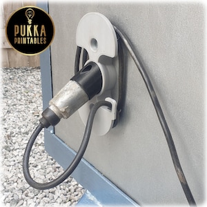 May include: A white charging cable holder with a black cable and a silver charging connector. The holder is mounted on a gray surface. The logo for Pukka Printables is in the upper left corner.