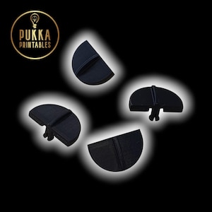 May include: Four black, semi-circular bottle stoppers with a vertical line detail are arranged against a black background. The logo "Pukka Printables" is in the upper left corner. The stoppers have a small, protruding base.