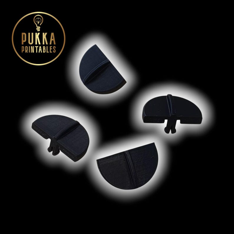 May include: Four black, semi-circular bottle stoppers with a vertical line detail are arranged against a black background. The logo "Pukka Printables" is in the upper left corner. The stoppers have a small, protruding base.