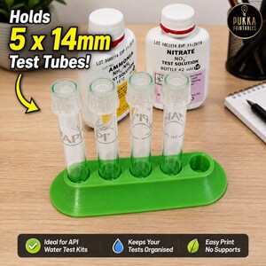 May include: A green plastic test tube rack with five circular slots designed to hold 14mm test tubes. Four clear glass test tubes are inserted into the rack. The rack is positioned in front of two white plastic bottles labeled Ammonia and Nitrate.