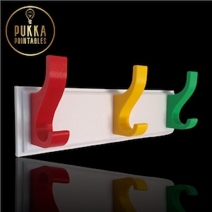 May include: A white wall-mounted coat rack with three coloured hooks. The hooks are red, yellow, and green, mounted on a white rectangular board. The logo "Pukka Printables" is in the upper left corner.