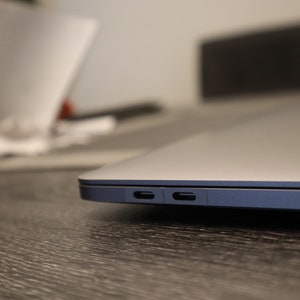 May include: Close-up of the side of a silver laptop computer with two ports on the right side.