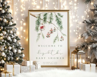 Può includere: Un cartello incorniciato con sfondo bianco raffigurante un ramo di pino ad acquerello con ornamenti in vetro appesi. Il testo recita: WELCOME TO lizabeth's BABY SHOWER DECEMBER 24TH 20XX THE PINE TREE PARK. La cornice è dorata.