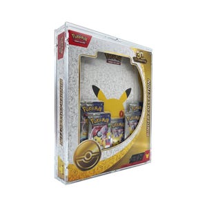 Op de afbeelding: Een doorzichtige acryl vitrine met een Pokémon 25th Anniversary Binder Collection set. De verpakking is voorzien van witte en gouden graphics met Pikachu-silhouetten, een gouden Poké Ball-embleem en diverse verzegelde trading card booster packs.