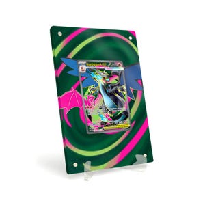 Puede incluir: Una tarjeta coleccionable de Pokémon enmarcada con una criatura con forma de dragón con acentos azules, negros y rosas. El marco tiene un fondo verde con un diseño en espiral rosa. La tarjeta se muestra en un soporte acrílico transparente.