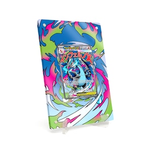 May include: A framed Pokémon trading card featuring a blue and gray dragon-like creature with flames. The frame has a colorful design with pink, blue, and green accents. The card is displayed on a clear stand.