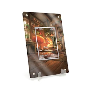 Könnte beinhalten: Ein klarer Acryl-Displayständer mit einer gerahmten Pokémon-Karte. Die Karte zeigt ein cartoonartiges fuchsähnliches Wesen mit dem Namen "Vulpix" und dem Wort "Stampede". Der Hintergrund ist eine detaillierte Illustration eines Raumes.