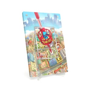 May include: A clear acrylic display featuring a Pokémon trading card with a Riolu character. The card is set against a cityscape backdrop with a red structure. The display is supported by a clear stand.