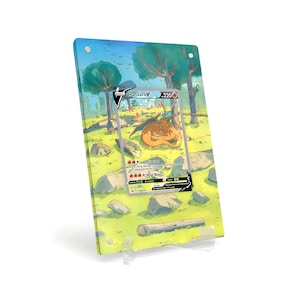 Könnte beinhalten: Eine Charizard V Pokémon-Karte, die in einem transparenten Acrylständer ausgestellt ist. Die Karte zeigt eine lebendige Illustration von Charizard in einer Waldlandschaft. Der Acrylständer wird von einem transparenten Kunststoffsockel getragen.