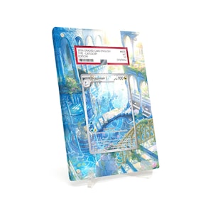 May include: A graded trading card featuring a Dragonair card with a blue and white illustration. The card is encased in a clear plastic holder with a scenic background. The holder has a label with text.
