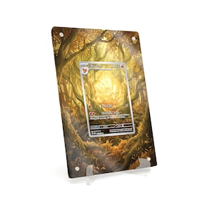May include: A framed Ninetales Pokémon card. The card features a golden fox-like creature with a forest background. The frame is clear acrylic, supported by a clear stand. The artwork has a warm, autumnal color palette.