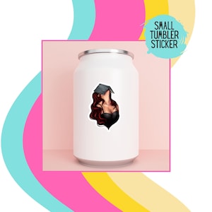 May include: A white tumbler with a sticker of a woman with long red hair wearing a black top and a graduation cap. The sticker says "SMALL TUMBLER STICKER".