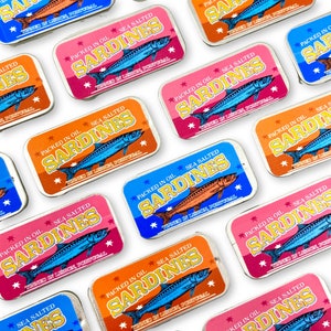 May include: A collection of colourful, rectangular tins with the words "Packed in Oil Sea Salted Sardines" and "Tinned in Lisbon, Portugal" printed on them. The tins feature a retro design with a blue and white illustration of a sardine.