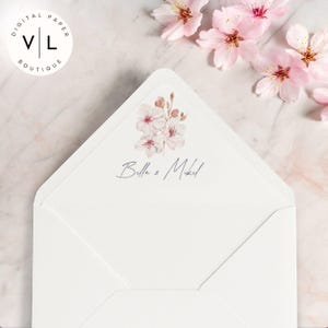 May include: White envelope with a pink floral design and the text "Bella & Mikel" in a cursive font.