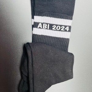 May include: Black socks with white stripes and the text "ABI 2024" in white.