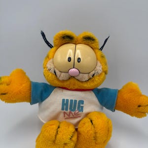 Peluche retro vintage de Garfield "Abrázame", gato, en camiseta, fabricado por Dakin, del programa de televisión de los años 80 (1978-1981), United Feature Syndicate.
