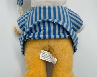 1990 年代のくまのプーさんがパジャマを着てベッドに座り、枕と